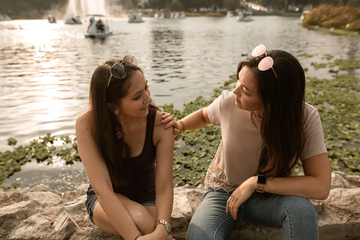 Two women talking beside a lake