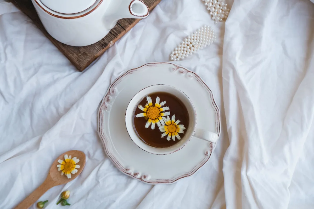 Cup of chamomile tea beside chamomile flowers