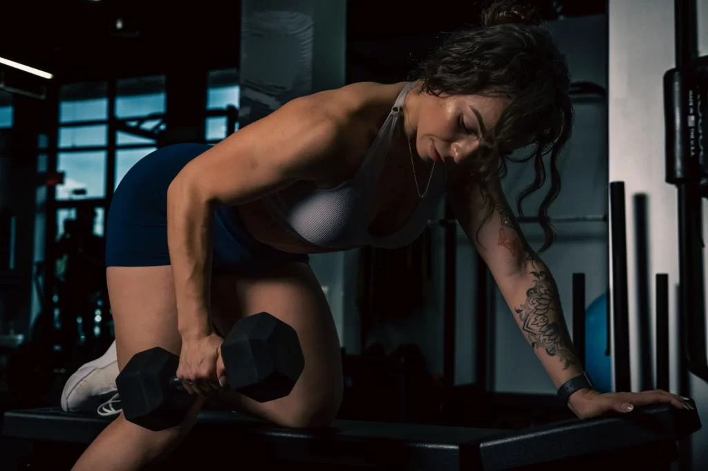 Woman doing a one-arm dumbbell row on a bench in a gym