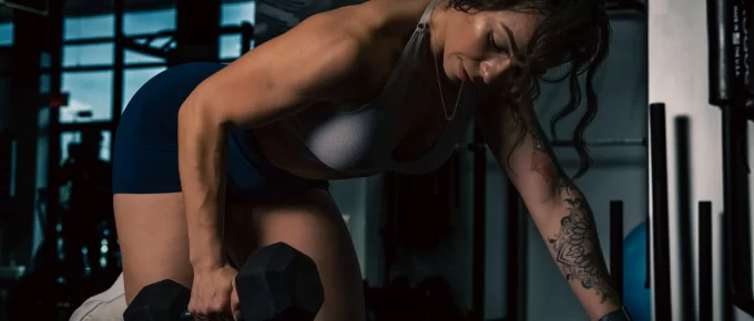 Woman doing a one-arm dumbbell row on a bench in a gym