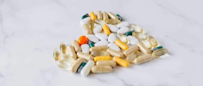 Mixed vitamin capsules and tablets arranged on a marble surface