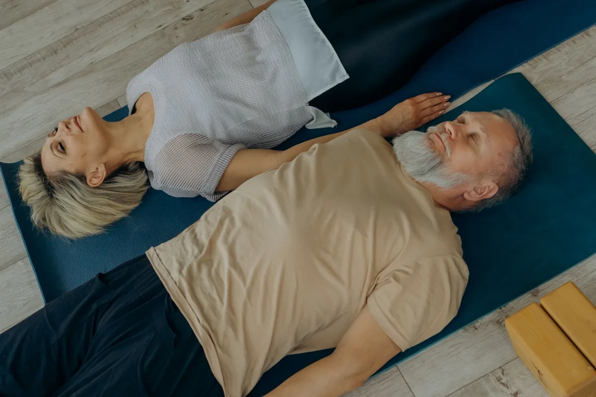 Two adults lying on exercise mats