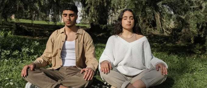 Two people sitting cross-legged outdoors