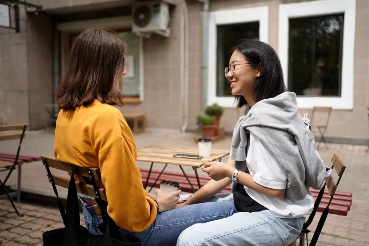 Two women talking at an outdoor cafe table