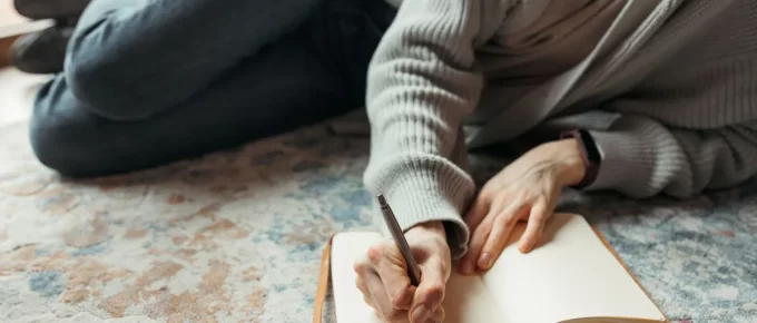 Person writing in an open notebook at home