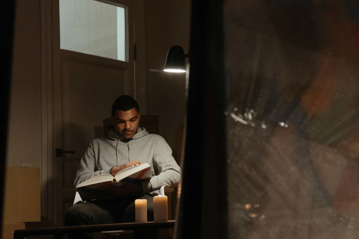 Man reading a book under a lamp at home