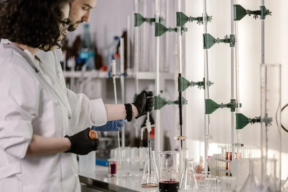Scientists handling glass equipment in a laboratory