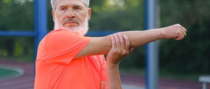 Mature man stretching his arm before exercising outdoors