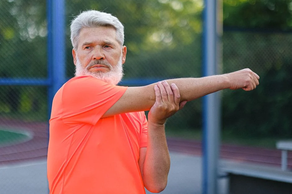 Mature man stretching his arm before exercising outdoors